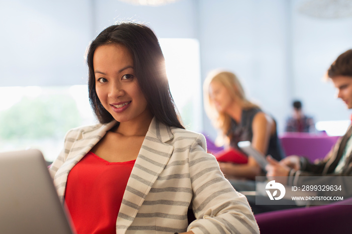 Portrait confident female college student with laptop student lounge