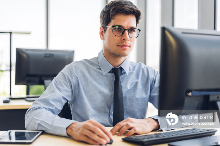 Handsome confident businessman relaxing looking at technology of desktop computer monitor while sitt