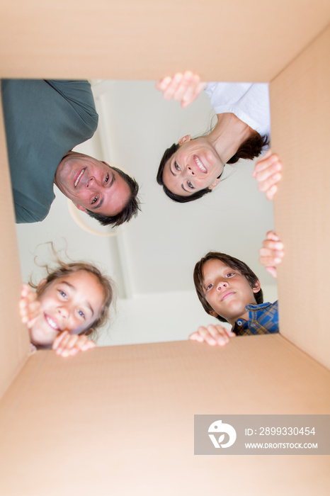 Portrait happy family looking into cardboard moving box