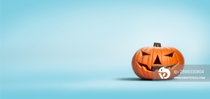 An unlit Halloween Jack O Lantern isolated on a widescreen pale blue background