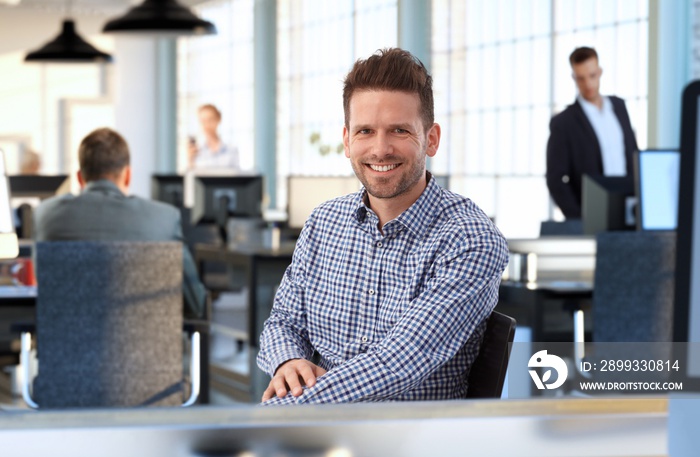 Casual man at desk in office smiling