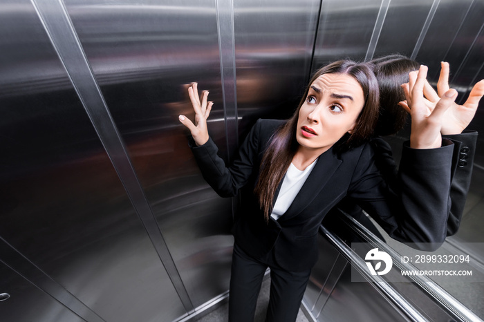 young scared businesswoman suffering from claustrophobia in elevator