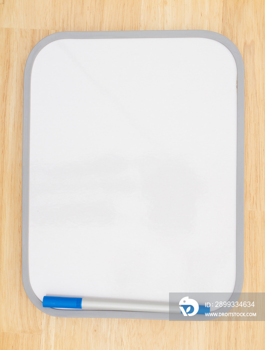 Blank white dry erase board with marker on wood textured background
