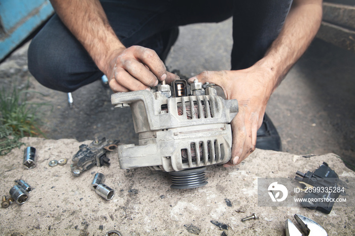 Man repairs car alternator. Service center