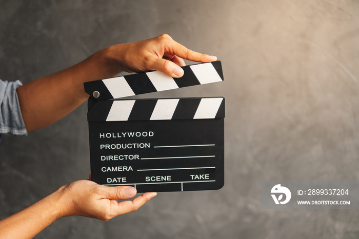 Women hands holding clapper board for making video cinema in studio.