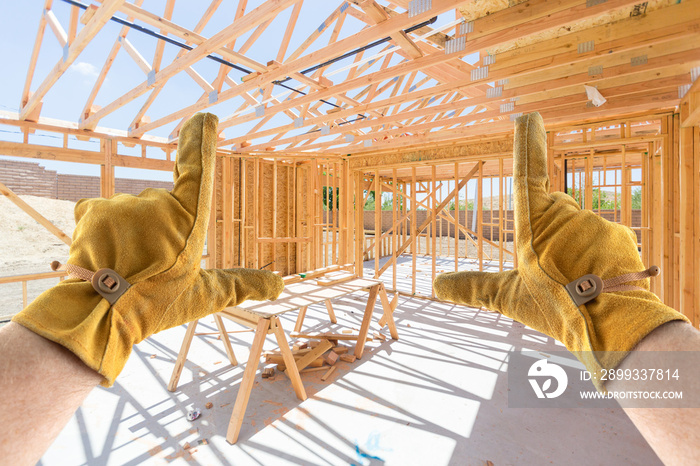 Male Contractor Hands Framing Unfinished House Framing At Construction Site