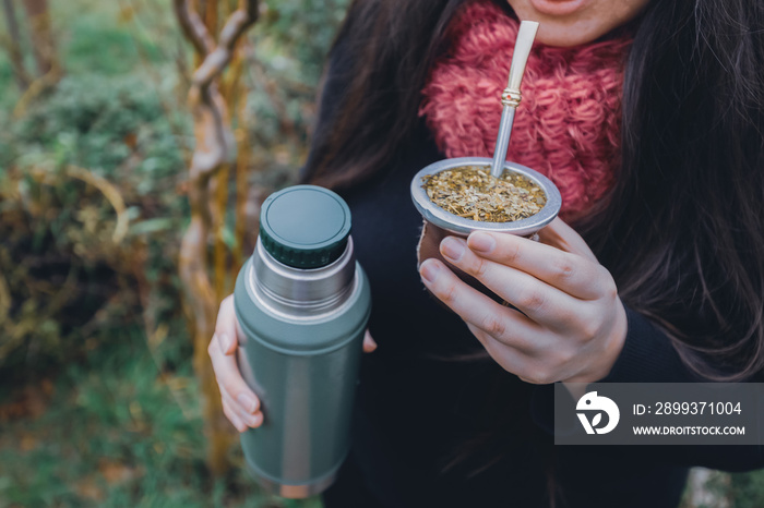 Young woman drinking mate in the park. Latin beverage.