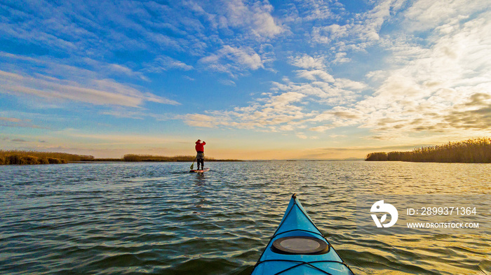 View from bow (prow) of blue kayak to the autumn lake at sunset. Autumn or winter kayaking.