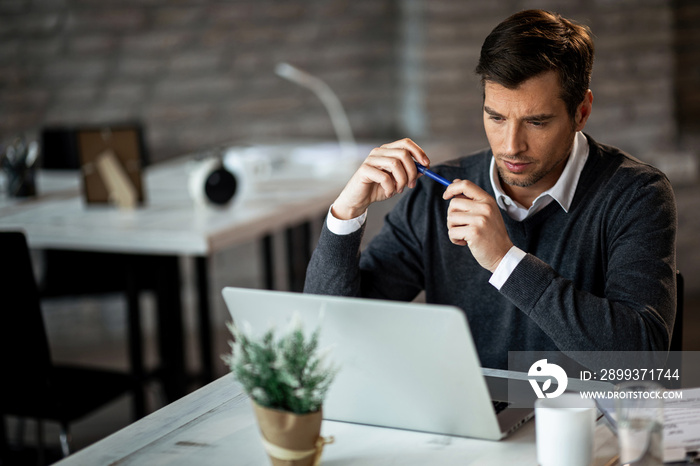 Concentrated businessman reading something on a computer while working in the office.