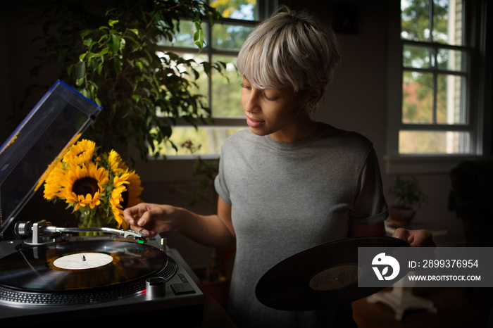 Young woman turning on turntable