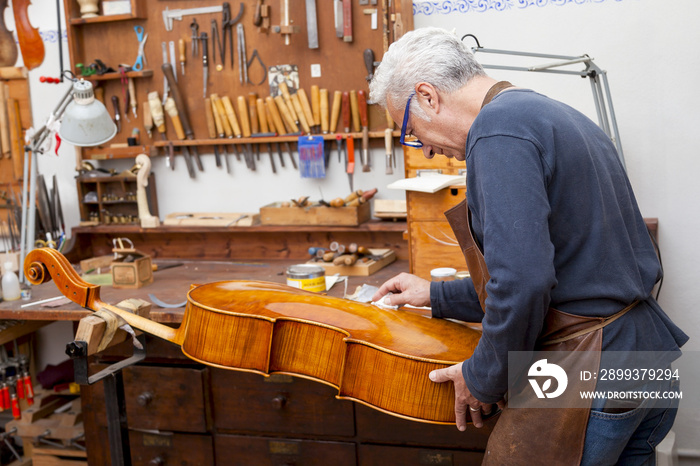 portrait of mature violin maker while testing the violins in his
