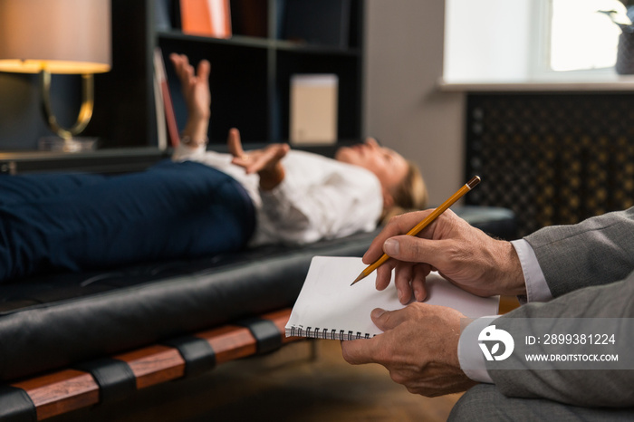 Male psychotherapists hands making notes in his notepad