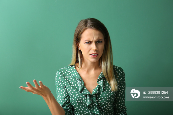 Indignant young woman on color background