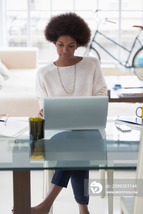 Young woman with afro working from home at laptop