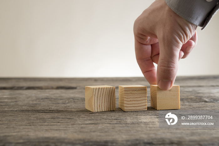 Three wooden empty blocks being placed on a rustic table