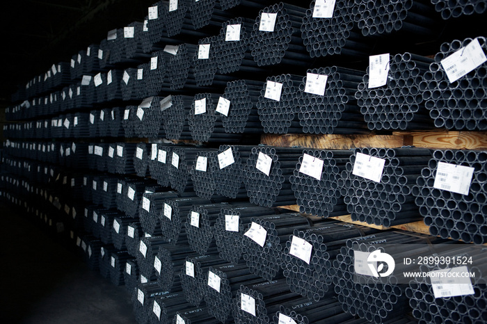 Stacks of metal pipes and rod on shelf in warehouse