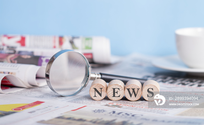 Newspaper and magnifying glass on the table, news wiritng on the cubes