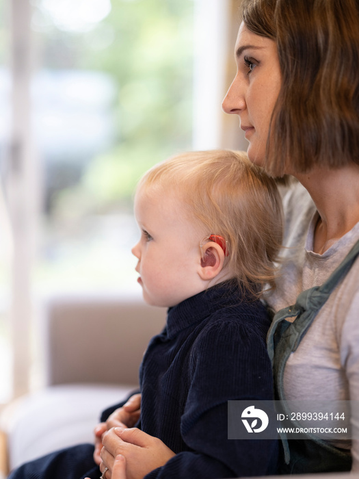 Daughter sitting on mothers lap at home�