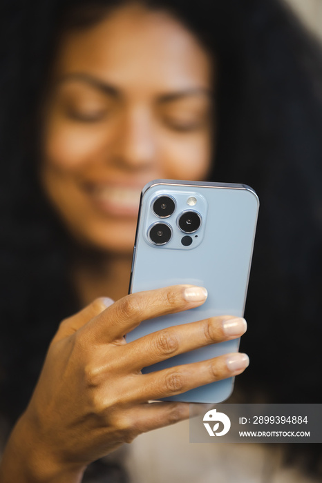 Happy black woman using mobile phone. Cheerful African female holding modern blue smartphone with tr