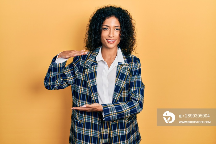 Young latin girl wearing business clothes gesturing with hands showing big and large size sign, meas