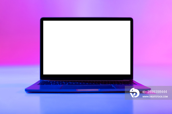 霓虹灯下的空白白色屏幕笔记本电脑，桌面或网站模型