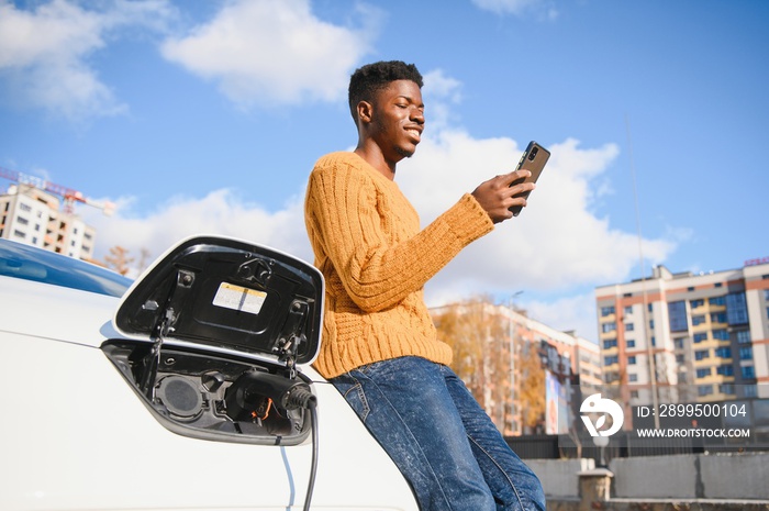 African American man charging his electric car.