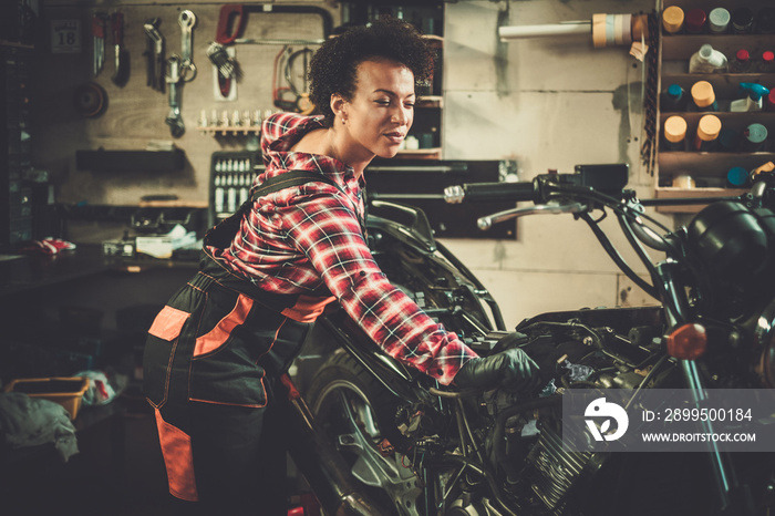 African american woman mechanic repairing a motorcycle in a workshop