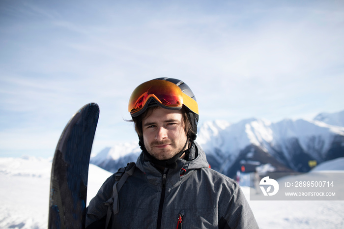 Junger Mann mit Snowboard Skihelm und Skibrille