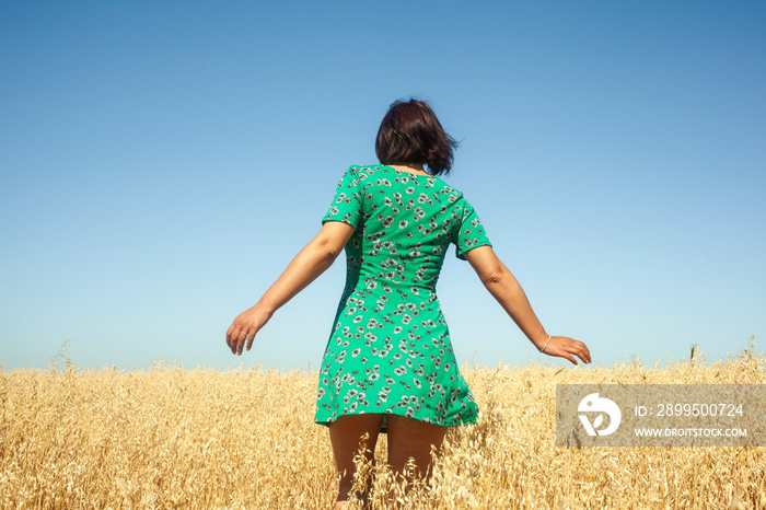 Woman with open arms in nature. Woman from behind walking with open arms in a short dress. Happy woman in nature with open arms embracing the fresh air. carefree young man walking in peace