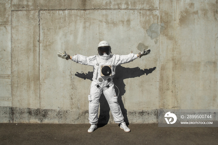 Futuristic astronaut in a helmet against gray walls. Fantastic Cosmic Costume.