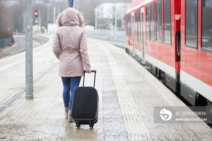 Junge Frau mit Koffer am Bahnhof