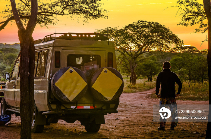 Adventurer or tourist and his 4x4 contemplating the sunset on the African savannah