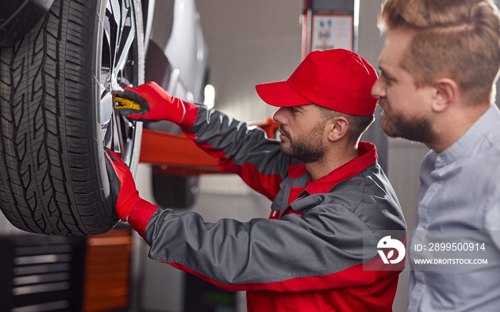 Mechanic with customer checking car wheel