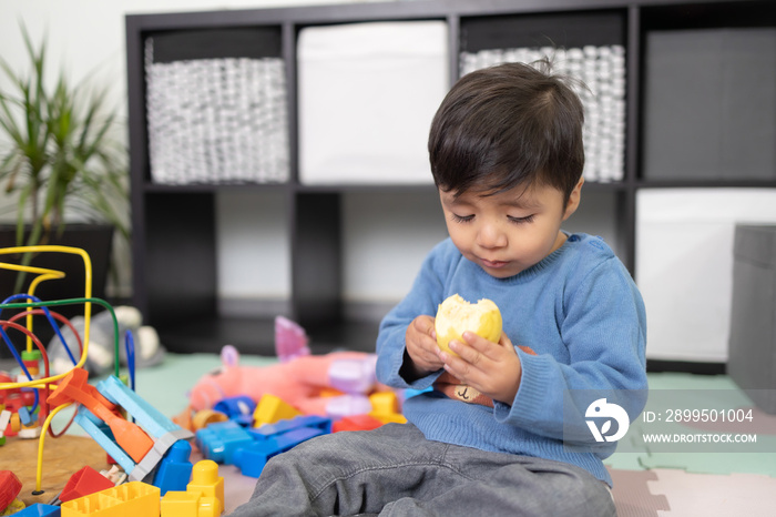 two years old mexican baby boy eating guayaba on messy room