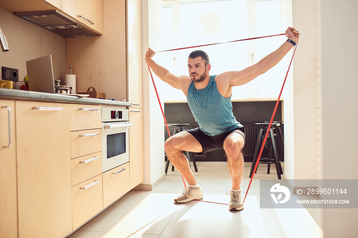 Handsome young man doing exercise with elastic fitness band