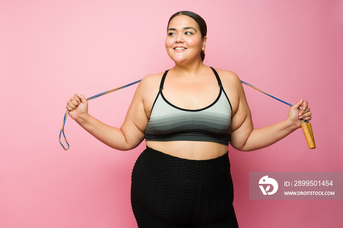 Smiling plus size woman in activewear jumping rope