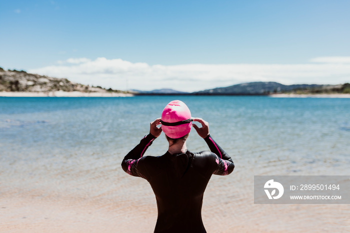 woman in her 40s wearing a neoprene and waiting to swim in the lake. Triathlon concept