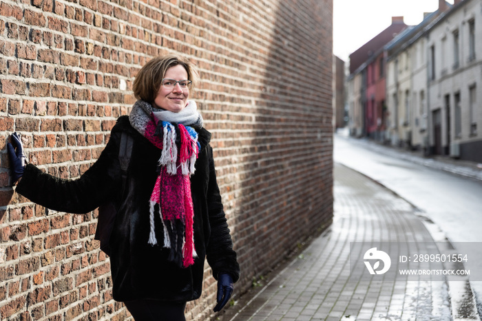 Attractive thirty year old woman posing against a brick wall in the streets of old town