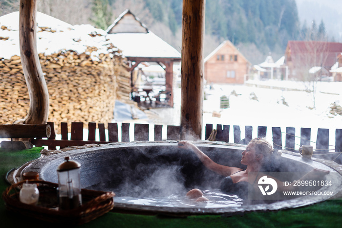 Young woman in an open air bath while snowing