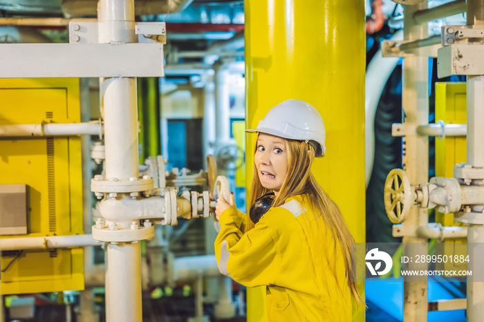 Young woman in a yellow work uniform, glasses and helmet in industrial environment,oil Platform or liquefied gas plant