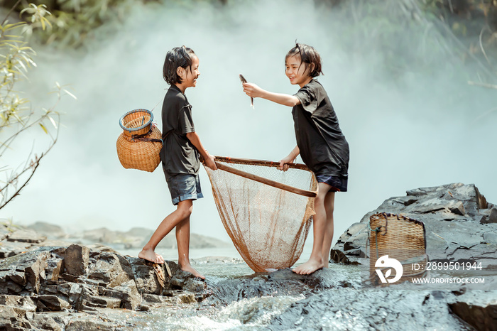 Two girls In the rural areas of Thailand Catching fish in the stream