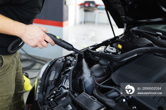 A man cleaning car engine, car detailing (or valeting) concept. Selective focus.