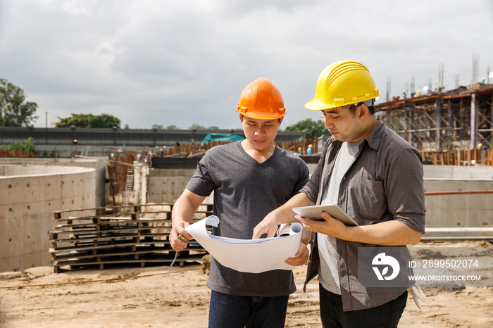 Team of construction workers discussing project details with blueprint in construction site.