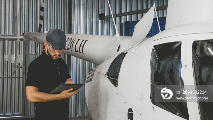 Male mechanic in uniform examining helicopter. Pre flight inspection at the airportы