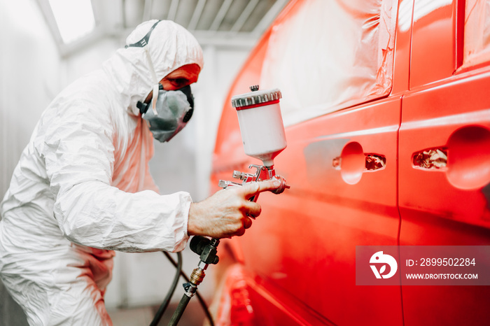 Close up details of mechanic worker, painting a red car