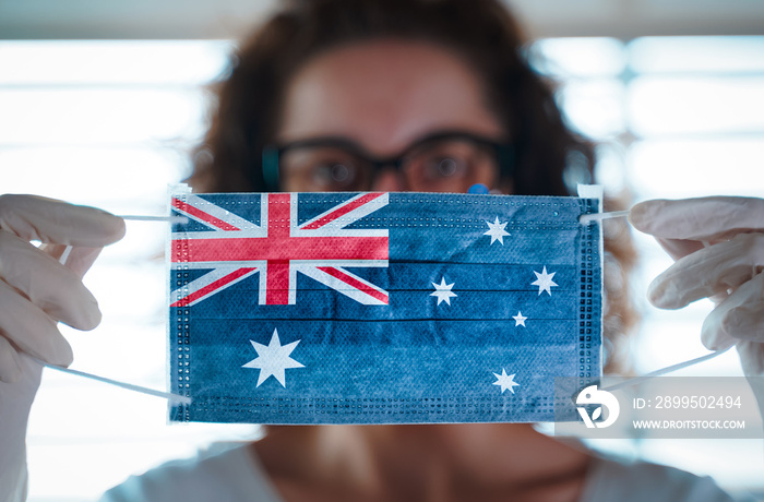 Pandemic Coronavirus. Close up of young woman with surgical mask with the flag of australia on it. Concept of Coronavirus, COVID-19, health emergency and quarantine