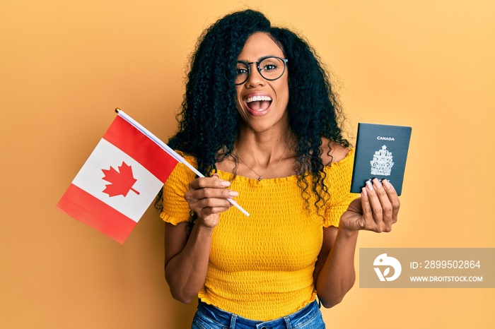 Middle age african american woman holding canada flag and passport celebrating crazy and amazed for success with open eyes screaming excited.