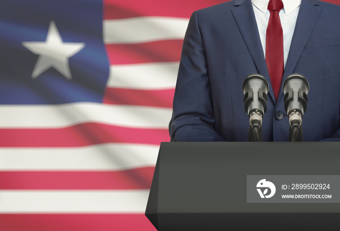 Businessman or politician making speech from behind a pulpit with national flag on background - Liberia