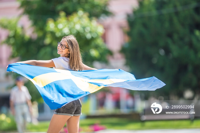 Happy girl tourist walking in the street with sweden flag