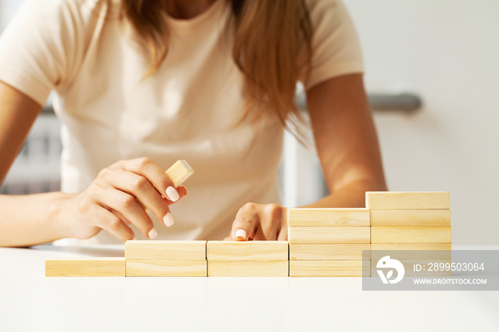 Women hand put wooden blocks in the shape of a staircase